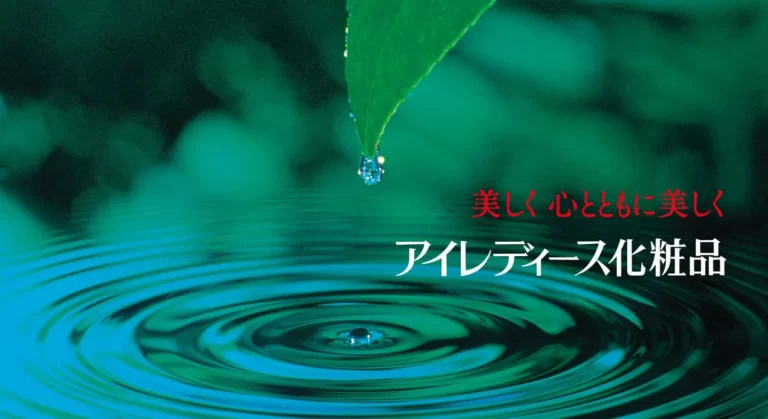 草の葉から一滴のしずくが水面に落ち、波紋が広がっていく「水の輪」の画像。「美しく心とともに美しく　アイレディース化粧品」